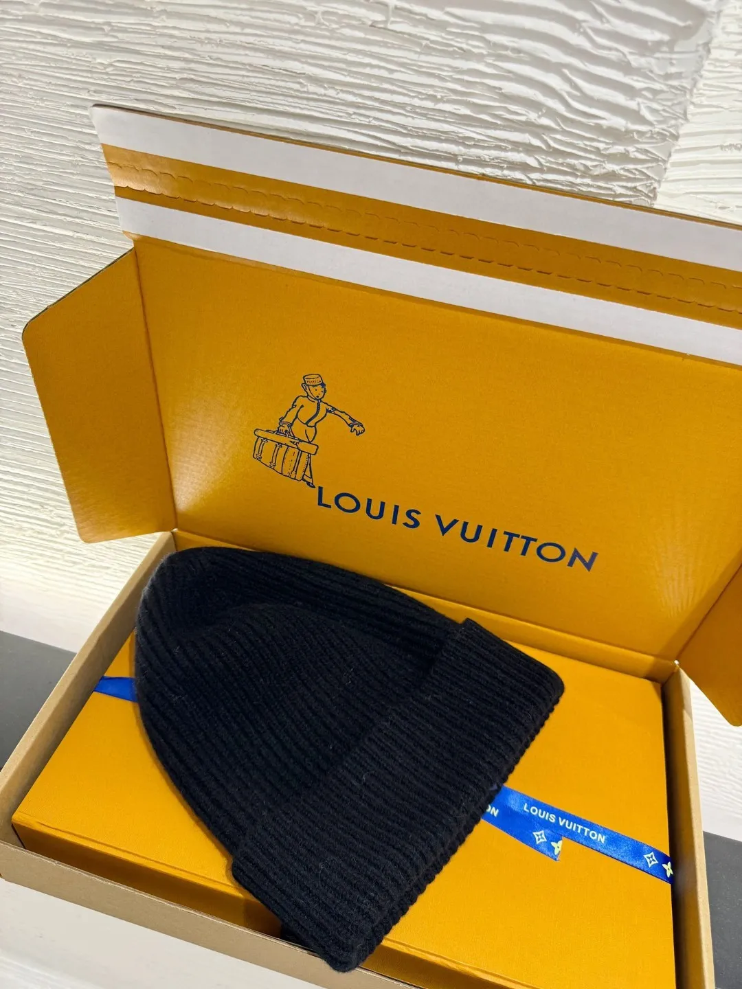 LOUIS VUITTON new embroidered wool cold hat ●Original version: 3800 purchase and development ●Item number: 1681973-A45 ●Fabric: wool blended fabric ●Technology: embroidery production ●Color: white/black ●Version: fitted version ●Description: This is LV The 2025 autumn and winter series logo embroidered knitted cold hat is made of 100% Italian virgin wool, woven with a 30-needle dense weaving process. The yarn twist reaches 600 twists/meter, which has both warmth and stiffness. The main body of the hat has a vertical grooved texture, which is elastically wrapped through fixed-spacing stitching techniques. The front logo of the hat uses three-dimensional appliqué technology, and the Monogram elements (quatrefoil, LV letters) are sewn with high-density embroidery threads of the same color. The edges are overlocked to prevent fuzzing and threading; the top of the hat is made of double-layer ribbing, which is durable and elastic and fits the ears. The finished product is shaped by high-temperature steam, and the three-dimensional shape of the hat is not easily deformed. The post-finishing process includes anti-static treatment, making it more comfortable for daily wear. The lining of the packaging is printed with the brand's classic "luggage maker" pattern, continuing the brand's retro luxury tone. The overall wiring is straight and delicate, the fabric is comfortable and soft, and the color is consistent without color difference. It can be matched with the same style to create a fashionable look and control various occasions. Customized accessories, complete with three standards, same style for men and women!